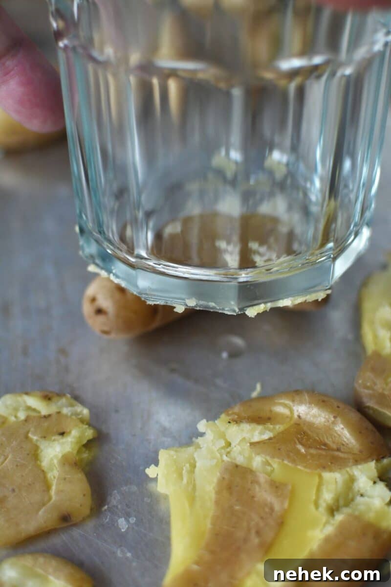 Crispy Smashed Potatoes with Garlic and Herbs 6 Smashing the potatoes on a tray with a sturdy glass.