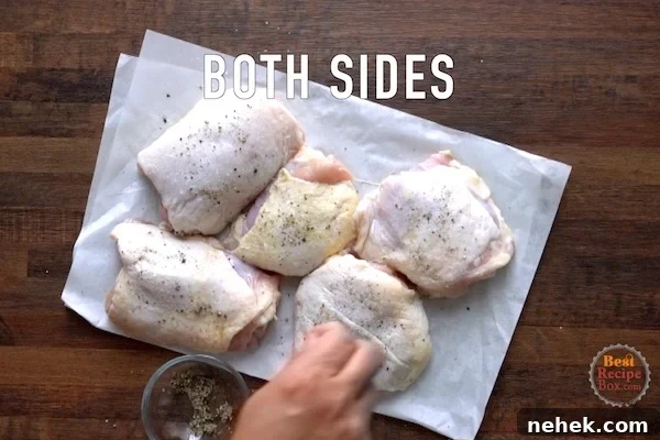 Seasoning raw chicken thighs with salt and pepper