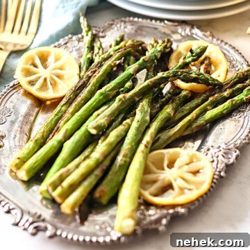 Roasted asparagus with lemons on a silver serving platter.