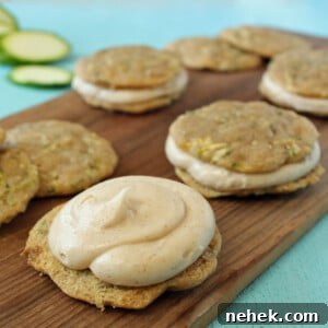 Several Zucchini Whoopie Pies on a wooden cutting board with the top off the front cookie to show the frosting.
