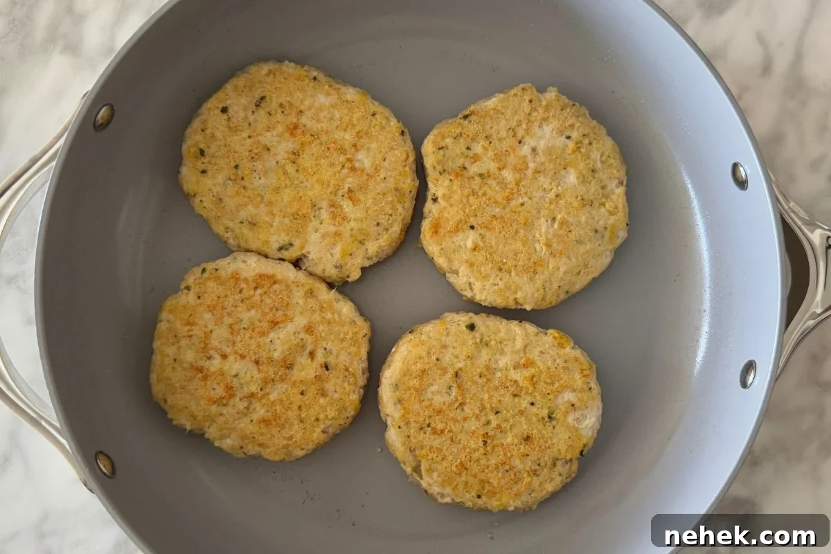 Chicken Parmesan Burger Recipe: Crispy, Cheesy Sandwiches 6 Chicken parmesan patties in a pan.