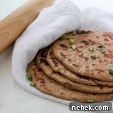 Flatbreads stacked on a towel next to a rolling pin