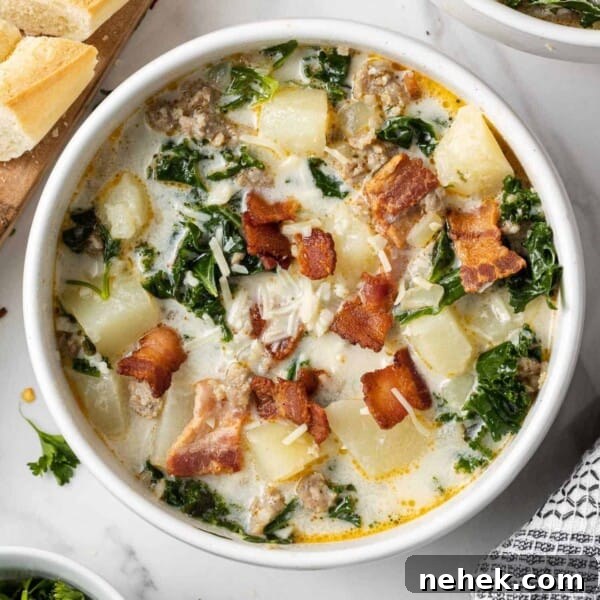 Overhead view of zuppa toscana soup in a white bowl garnished with crispy bacon.
