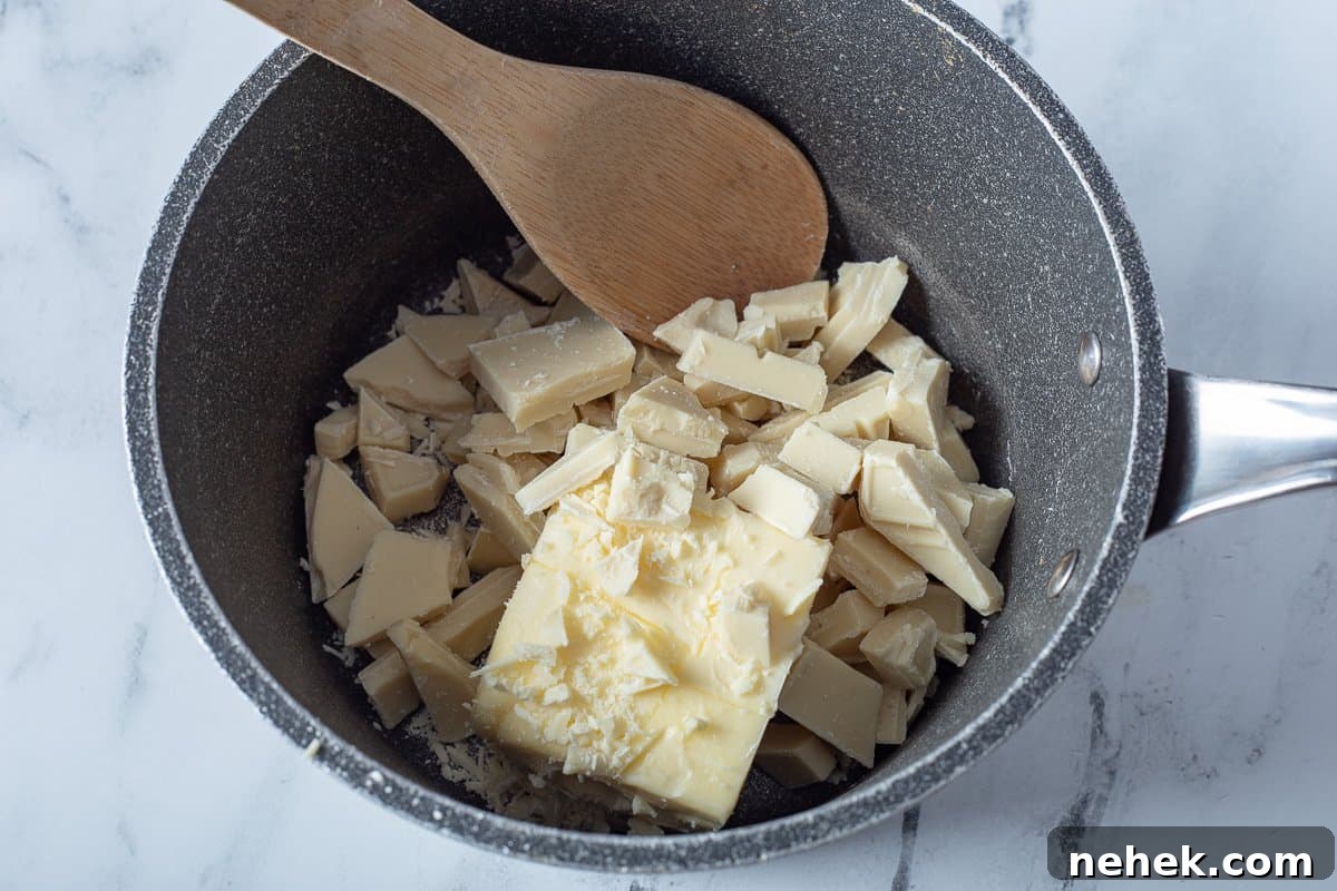 White chocolate and butter in saucepan with wooden spoon.