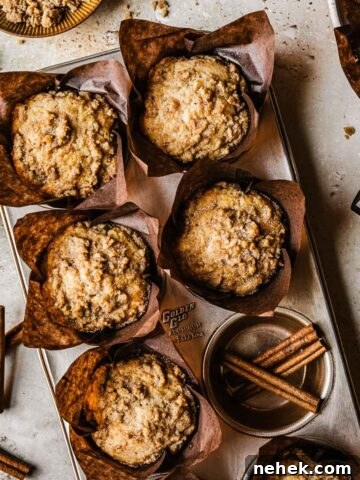 Streusel topped muffins in brown paper parchment liners in a muffin tin.