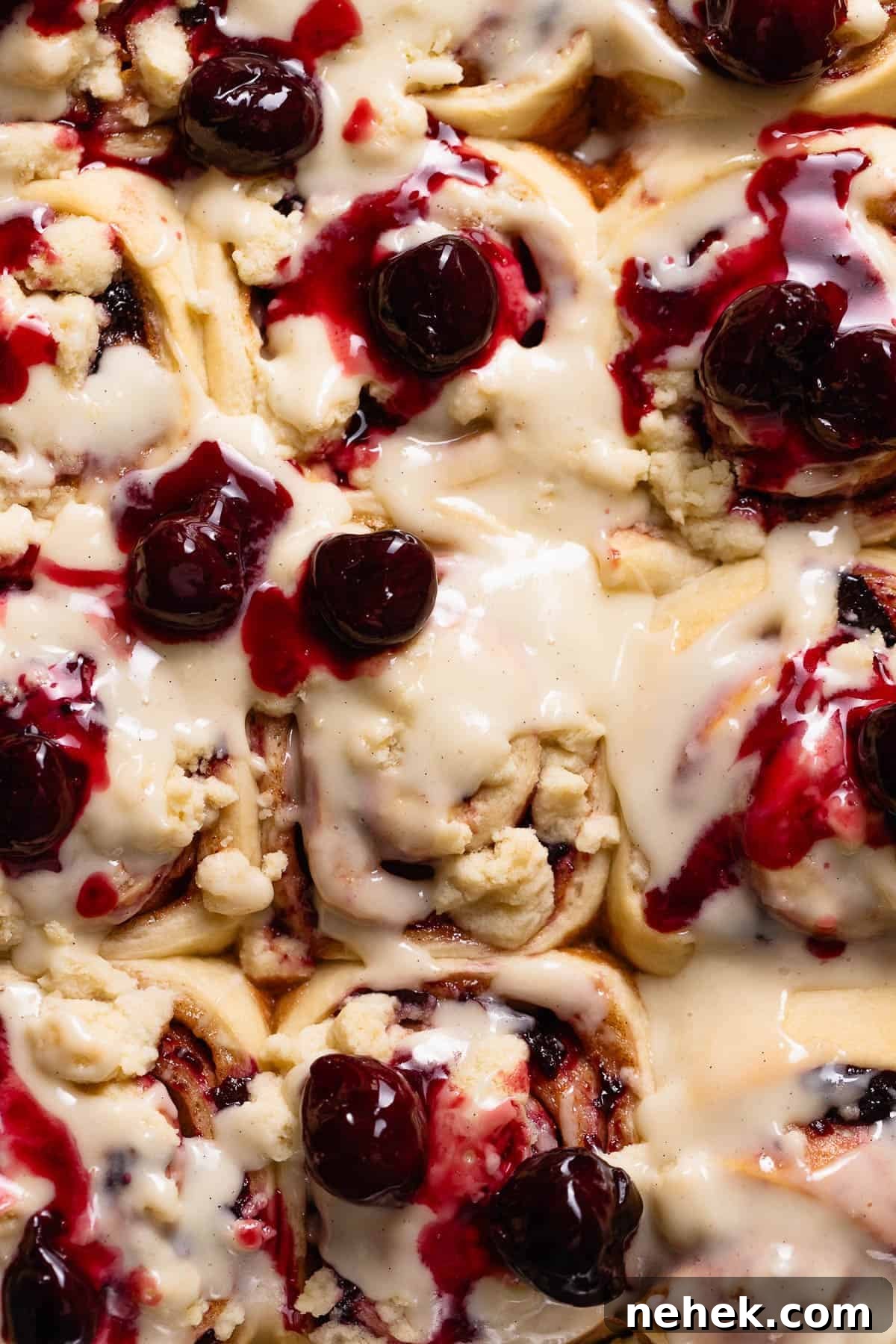 Cherry Pie Rolls with Crunchy Pie Crumb Topping 12 Overhead view of cherry cinnamon rolls in a baking pan topped with cream cheese frosting and swirled with juicy cooked cherries.