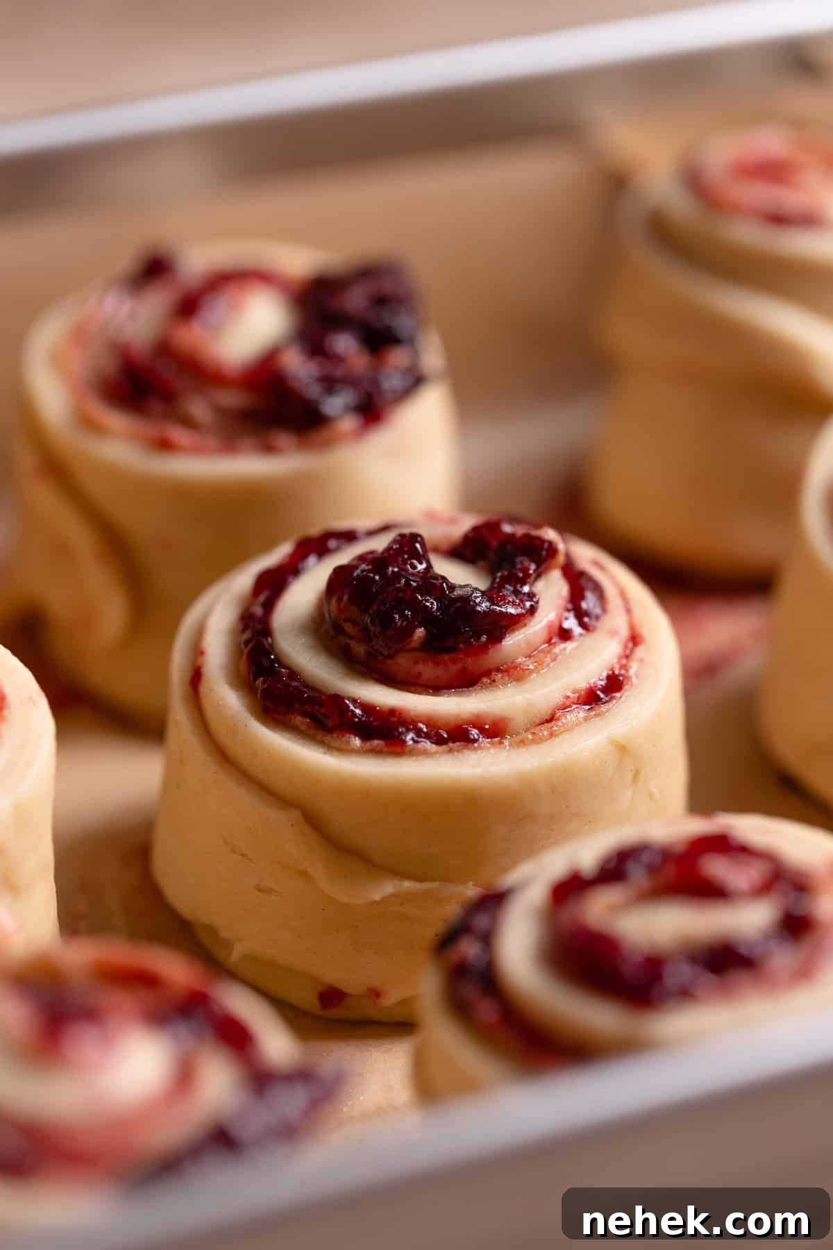 Cherry Pie Rolls with Crunchy Pie Crumb Topping 10 A close up view of an unbaked cherry cinnamon roll in a baking pan.