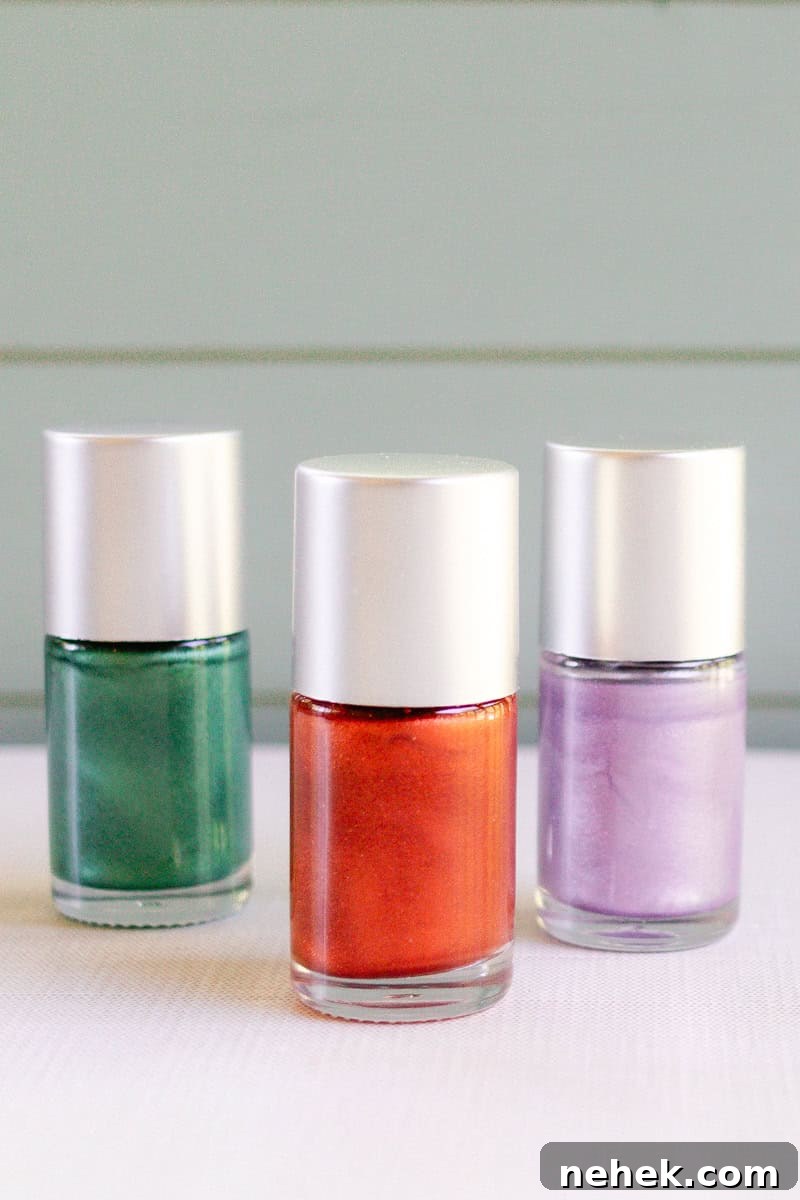 Three bottles of homemade nail polishes lined up on a counter. They are colored green, red, and purple. 