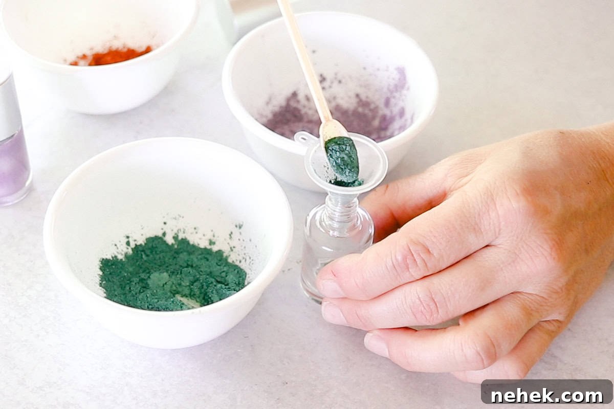 Scooping teal mica powder into an empty nail polish bottle with a small funnel in the neck. 