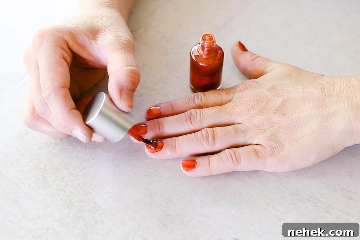 Painting fingernails with a red homemade nail polish. 