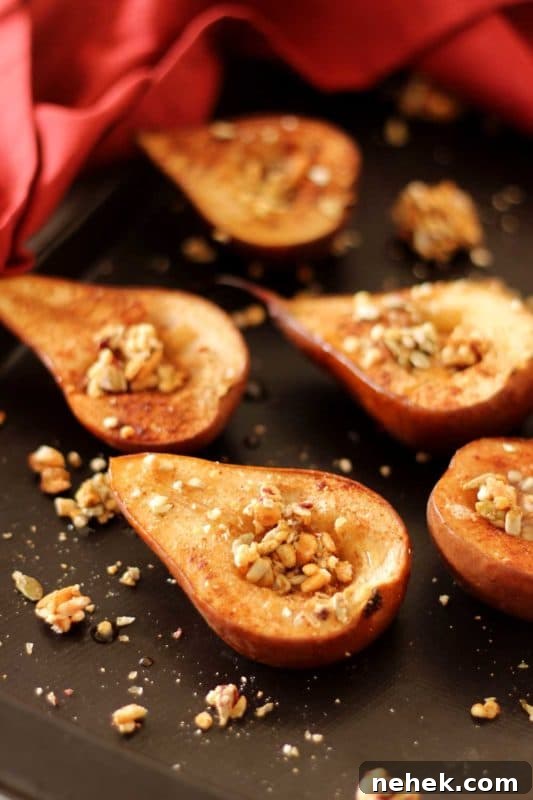 Maple Vanilla Baked Pears with Crunchy Granola Topping 2 Brown pan containing 5 baked pear halves topped with granola, red napkin in background.