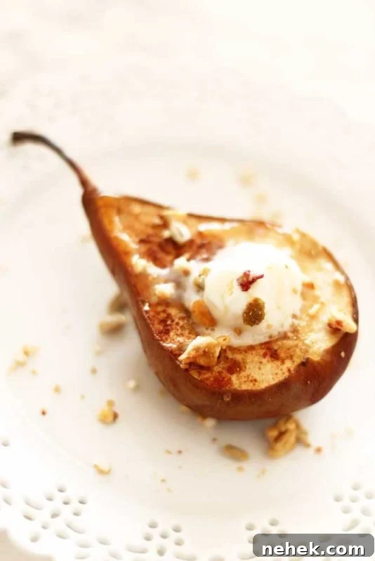 Maple Vanilla Baked Pears with Crunchy Granola Topping 10 Baked pear topped with granola and ice cream, sitting on a white plate.