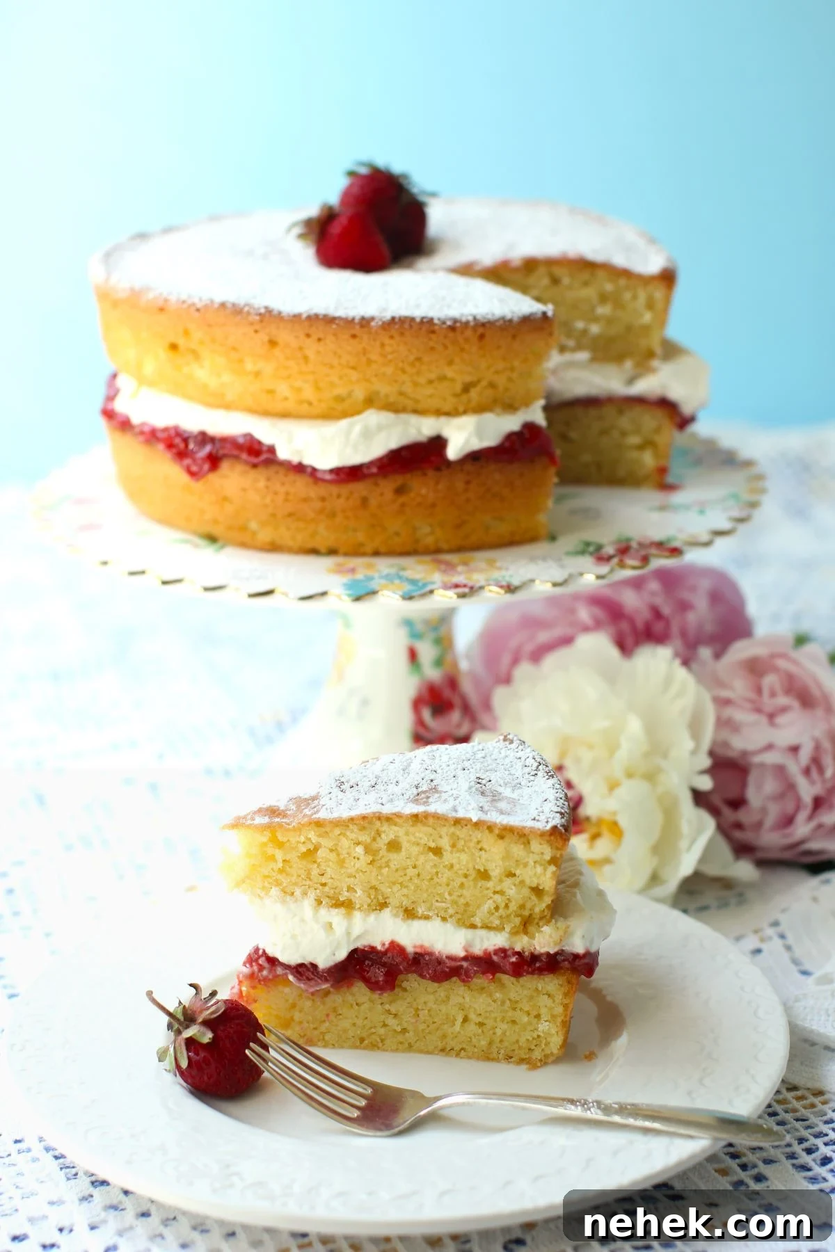 Gluten free Victoria Sponge Cake on cake stand with cut piece on plate in front.
