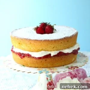 Thumbnail photo of a Gluten Free Victoria Sponge Cake on a cake stand, with strawberries on top.