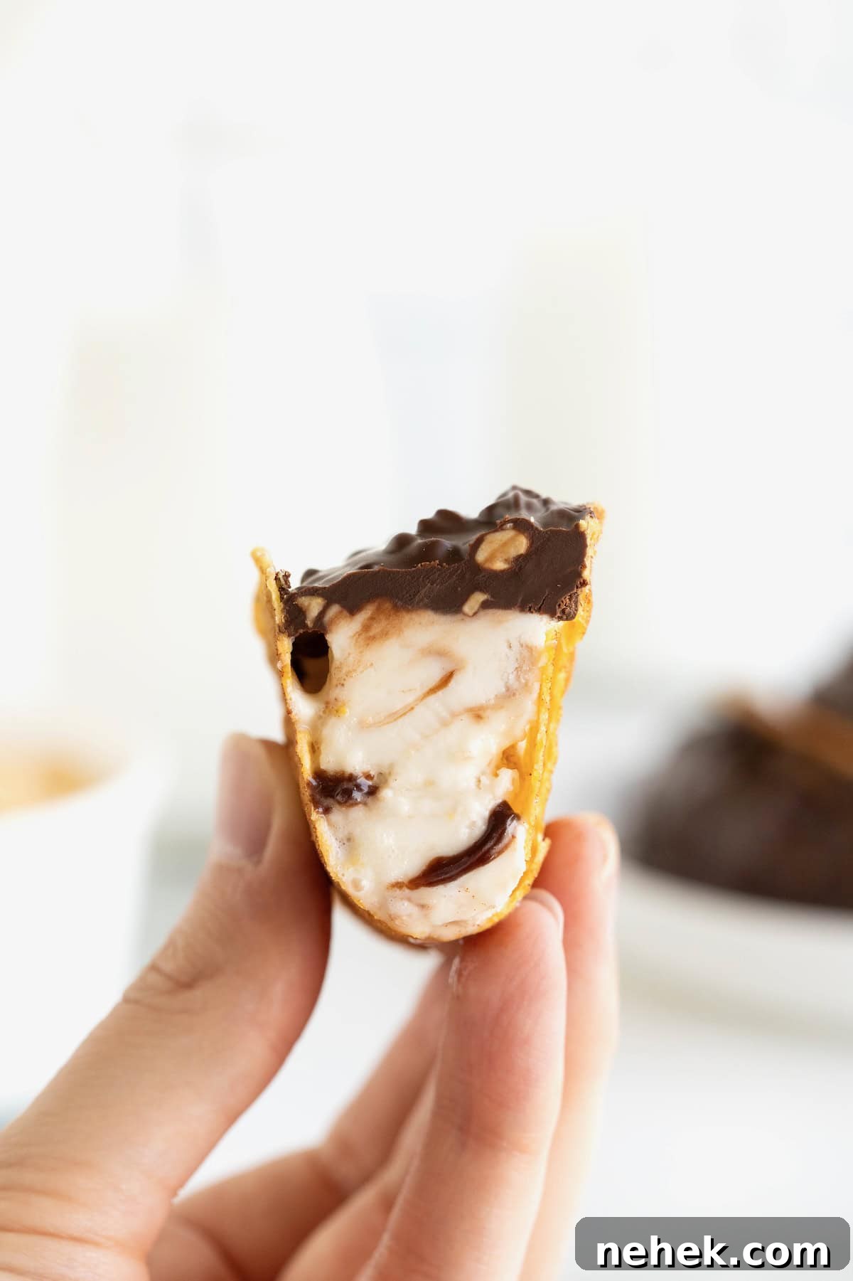 How to Make Homemade Chocolate Tacos: Step-by-Step Recipe 3 A hand holding a chaco taco with a bite out of it revealing the ice cream inside.