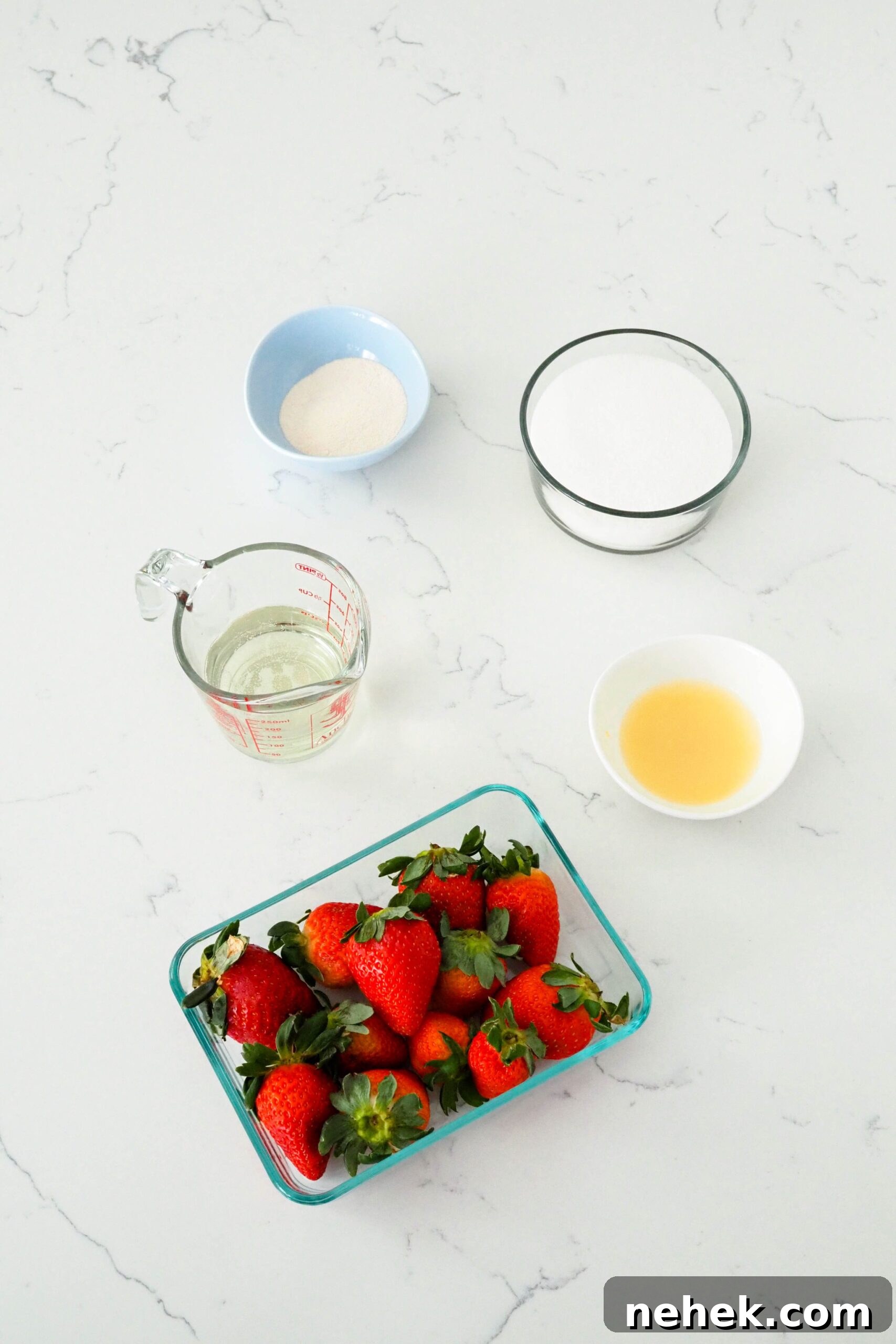 Pectin, sugar, lemon juice, strawberries, and champagne on a white quartz counter.