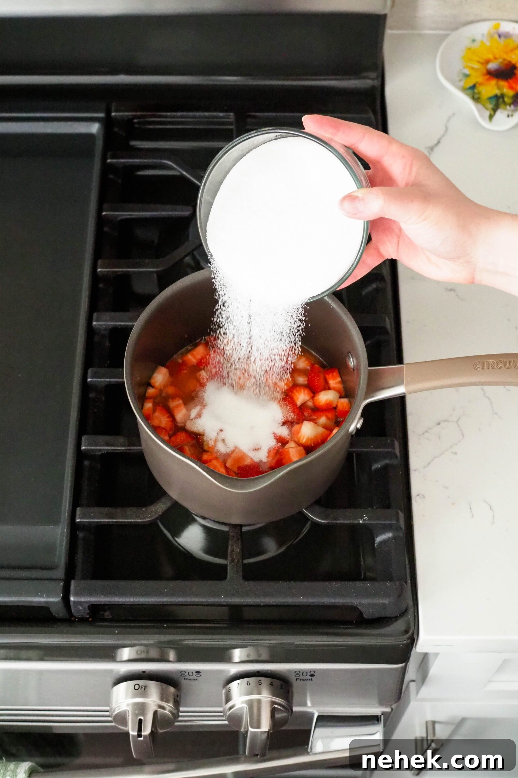 Sugar is poured into a saucepan with diced strawberries.