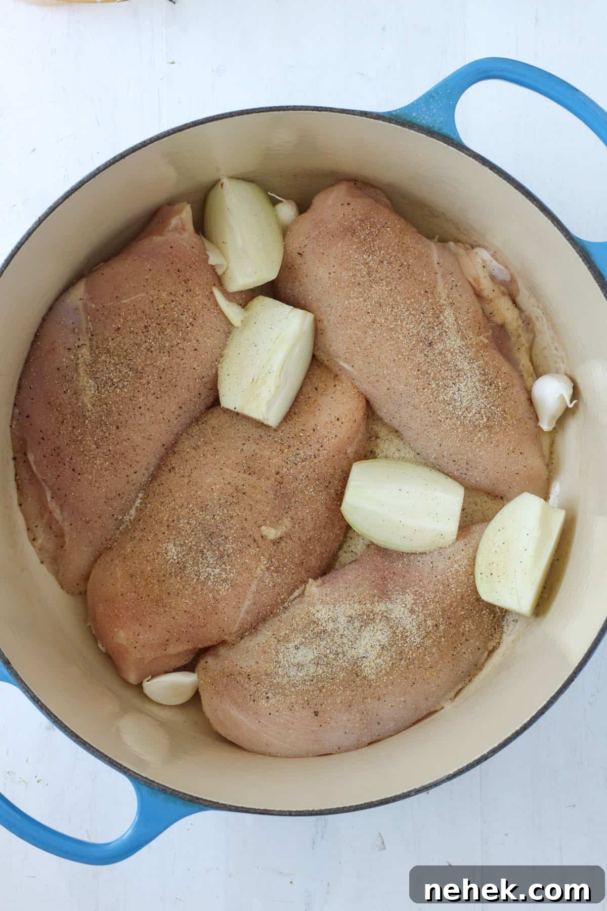 chicken breasts with quartered onions and garlic cloves in a Dutch oven.