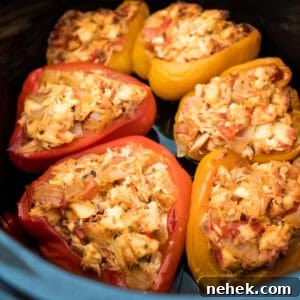 Cooked bell peppers in a slow cooker stuffed with feta, chicken, vegetables, and spices.