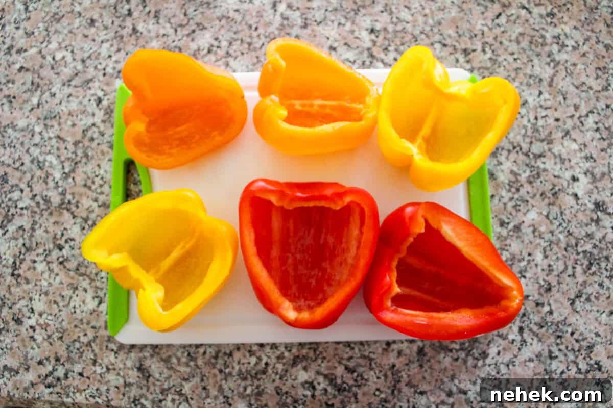 Three tri color bell peppers sliced in half for six halves sitting on a cutting board with stems and seeds removed.