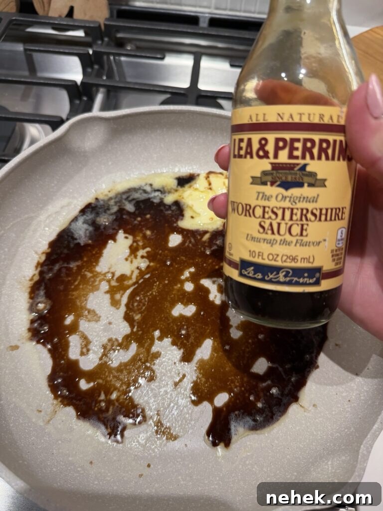 A bottle of Worcestershire sauce over a pan sizzling with the sauce and butter