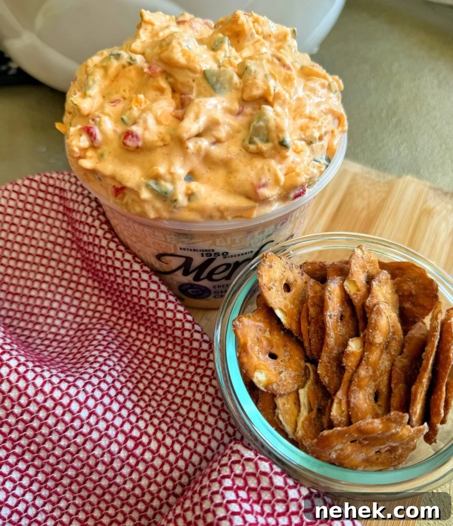 A cup of Lake House Pickle Pimento Cheese next to a cup of pretzel crackers