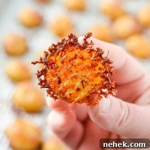 A hand holding a halved baby potato encrusted with parmesan cheese.