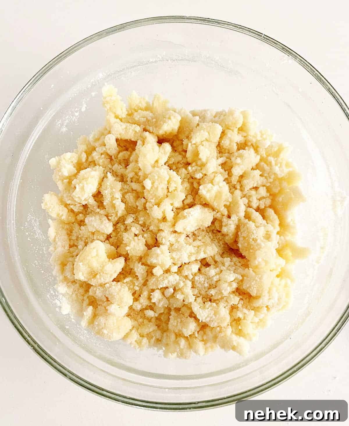 Dump cake topping mixture in glass bowl an a white surface.