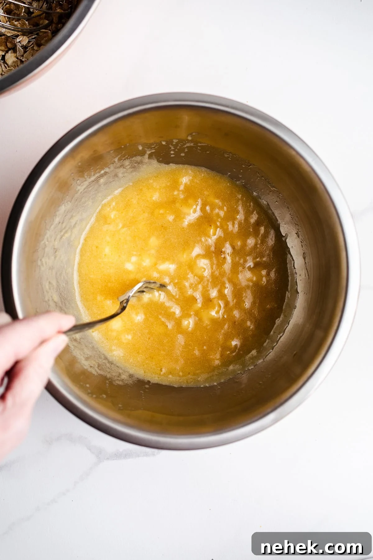 Mashed banana and maple syrup in a mixing bowl.