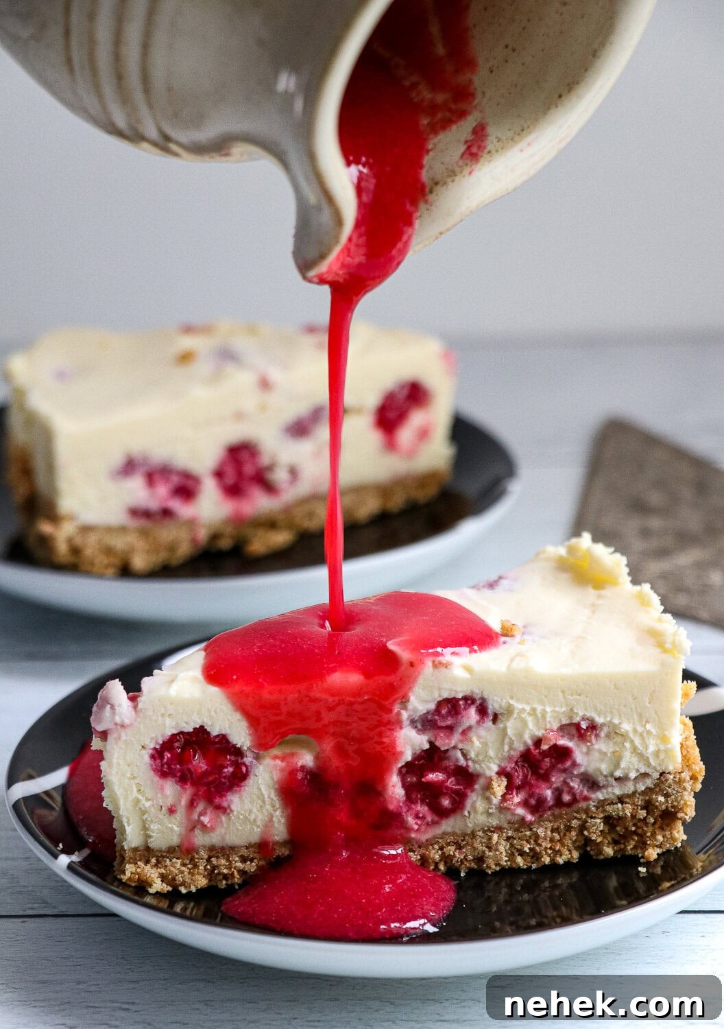 No Bake White Chocolate Raspberry Cheesecake Slice with raspberry coulis