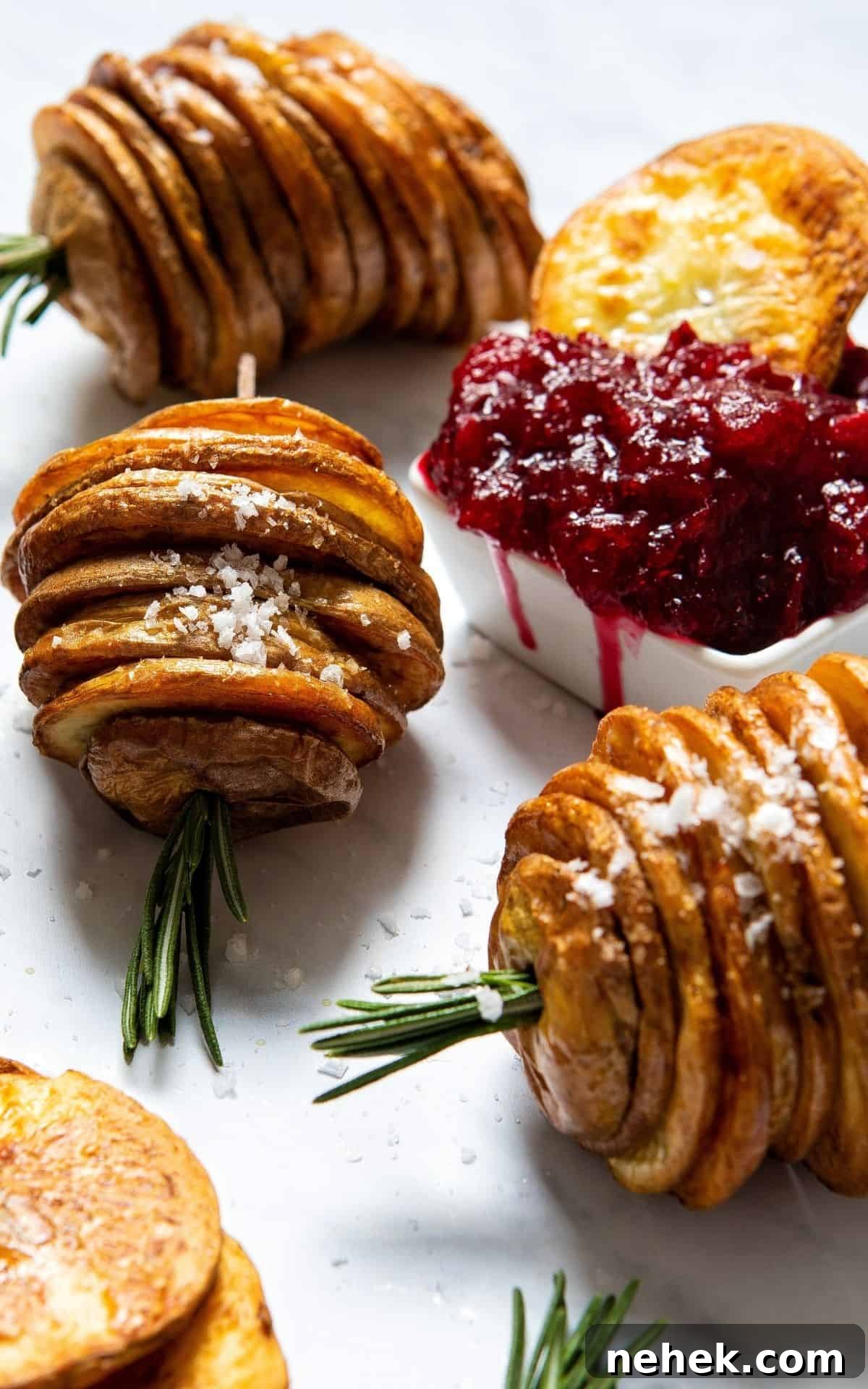 Roasted potato Christmas trees placed by a bowl of cranberry sauce.