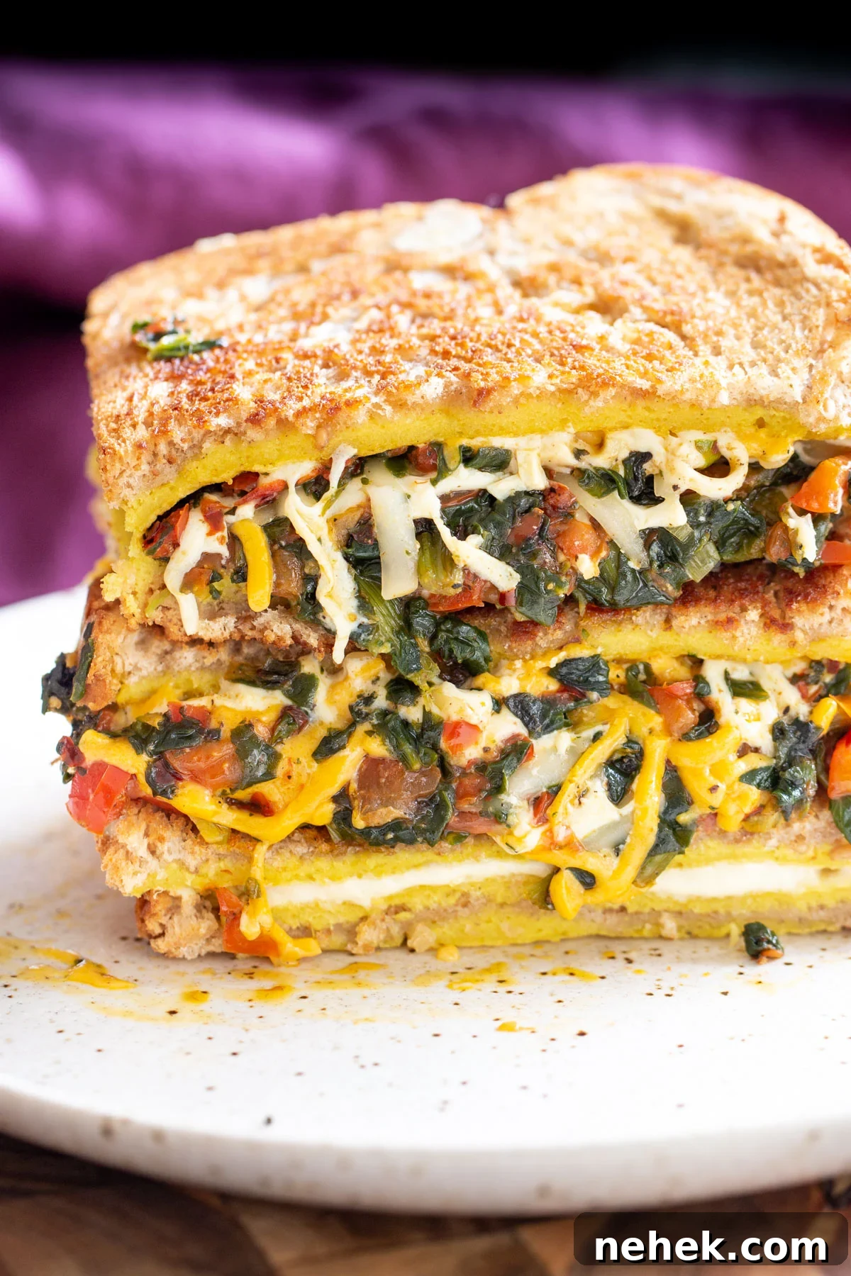 Vegan Moong Egg Sandwich Recipe: Protein-Packed Plant-Based Breakfast 10 slacked spinach and cheese vegan egg sandwich on a white plate