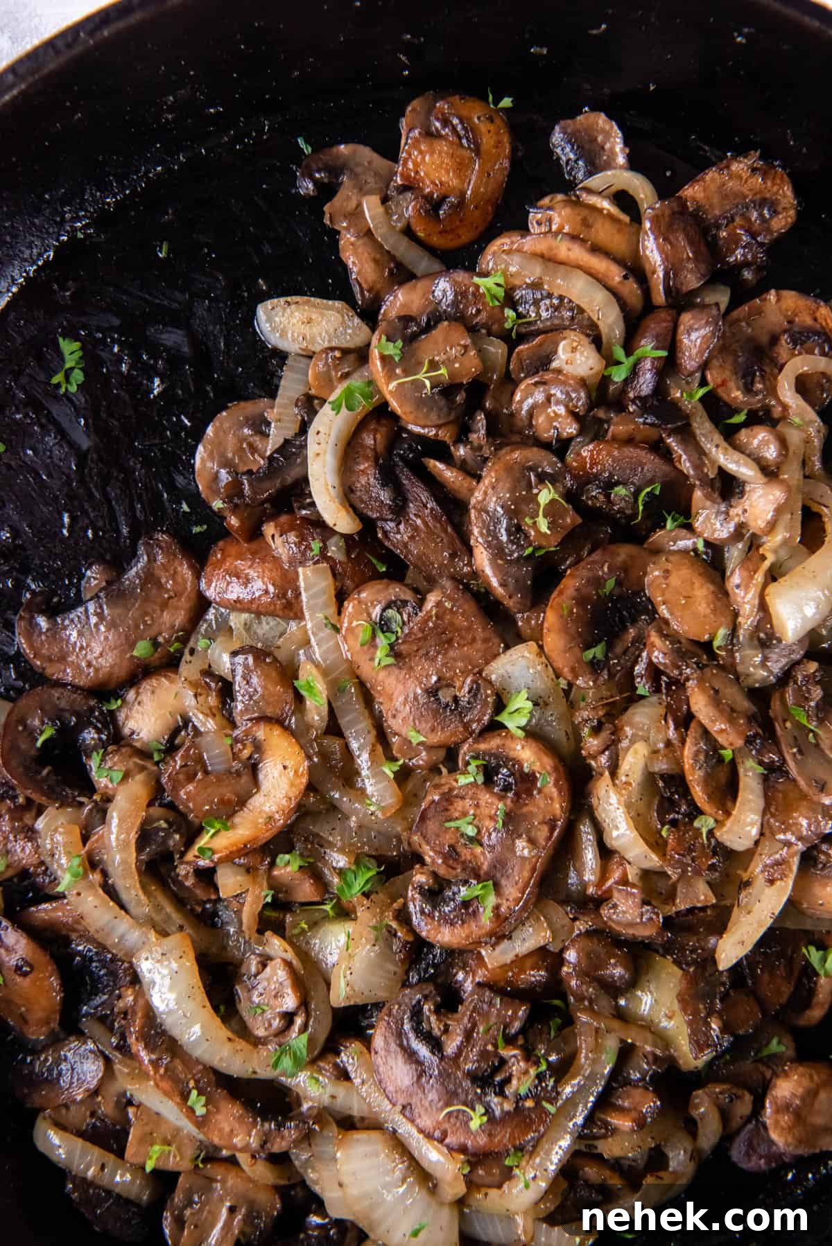 Sauteed mushrooms and onions in a black cast iron skillet after cooking.