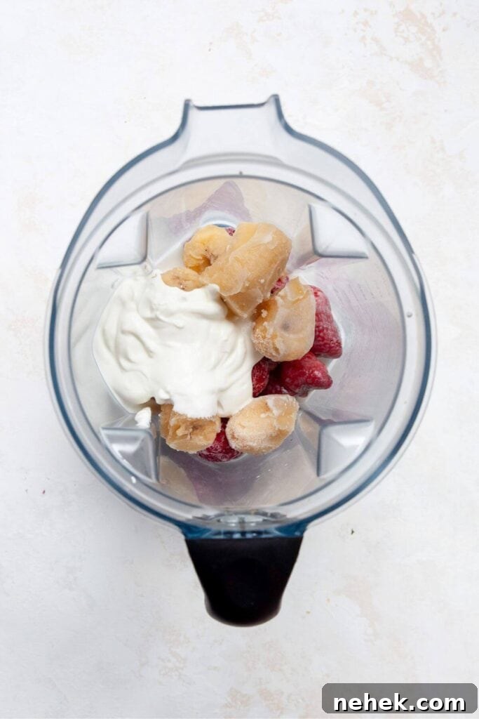 Creamy Strawberry Smoothie Bowl Recipe with Fresh Toppings 4 Frozen strawberries, banana, Greek yogurt, and milk in a blender before blending for smoothie bowl