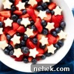 A bowl of patriotic fruit salad on blue cloth.