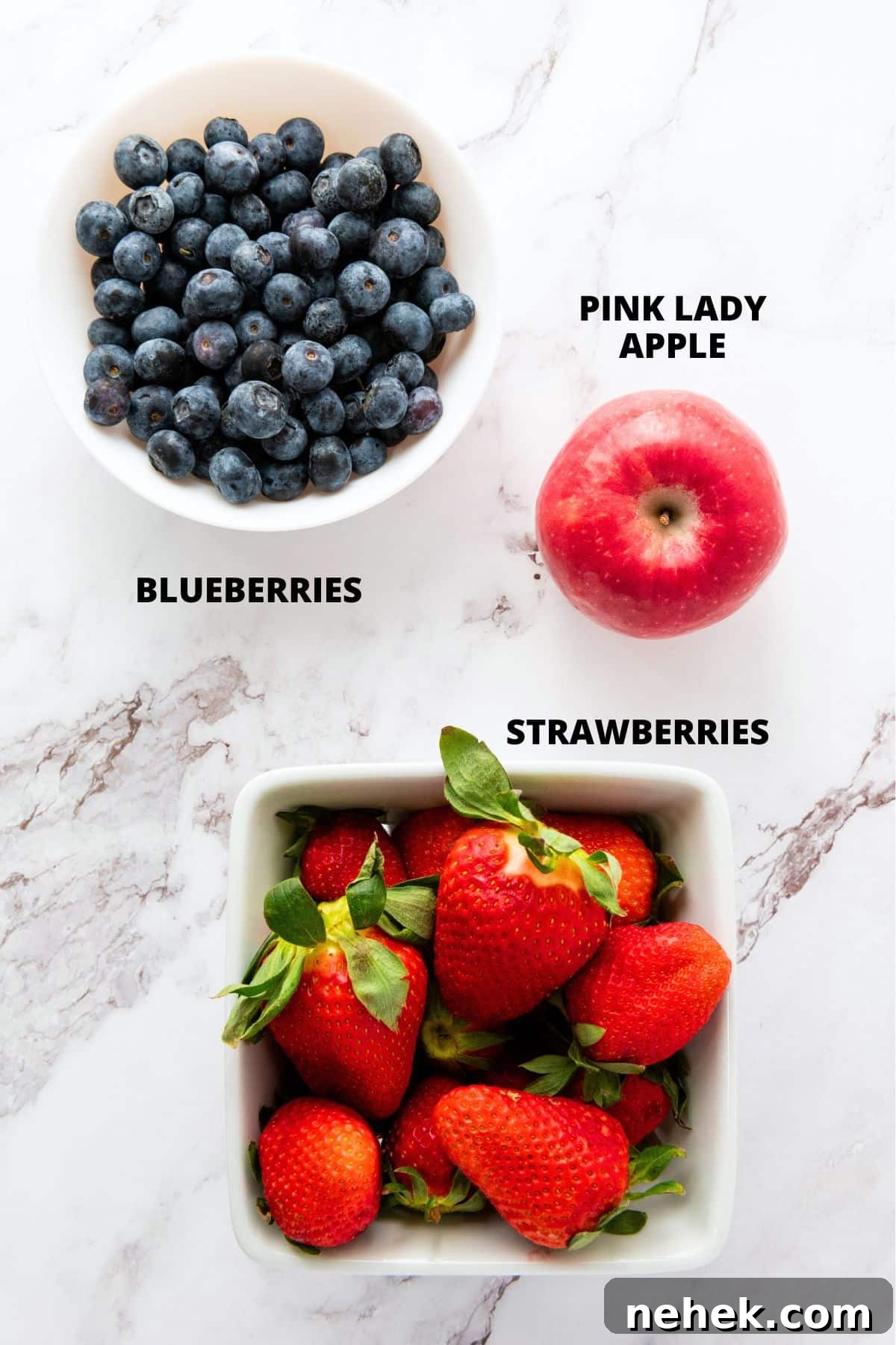 Ingredients for patriotic fruit salad recipe laid out on marble board.