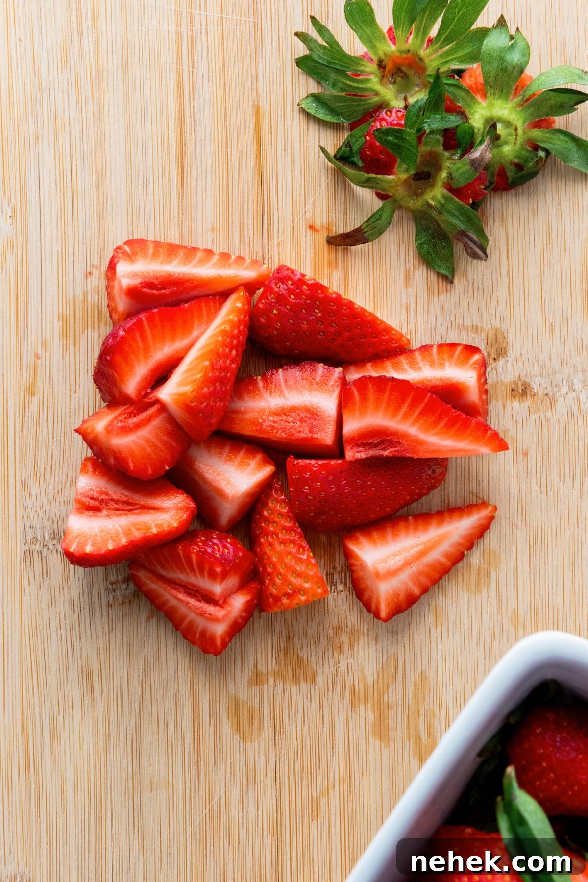 Sliced fresh strawberries on wooden board.