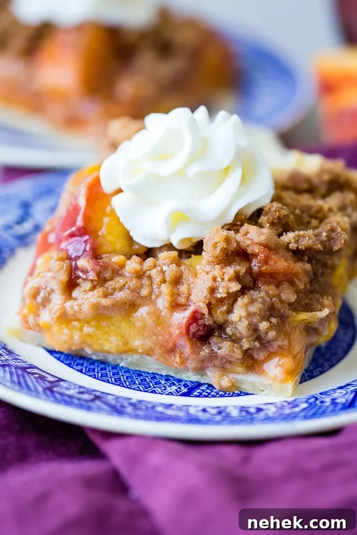 Brown Sugar Peach Pie Bars Recipe — Sticky Peach Dessert Bars 2 A purple napkin under a vibrant blue china designed dessert plate with a slice of brown sugar peach pie bars with a piped whipped cream dollop on top