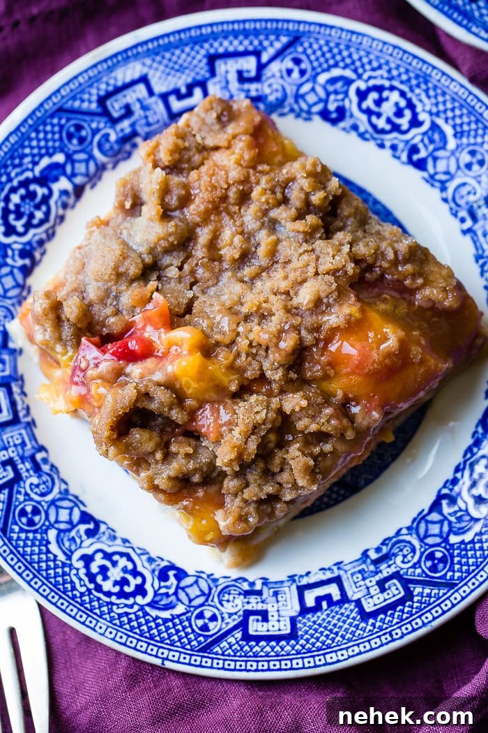 Brown Sugar Peach Pie Bars Recipe — Sticky Peach Dessert Bars 3 A purple napkin under a vibrant blue china designed dessert plate with a slice of brown sugar peach pie bars