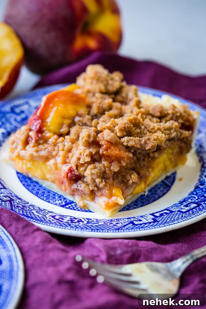 Brown Sugar Peach Pie Bars Recipe — Sticky Peach Dessert Bars 5 A purple napkin under a vibrant blue china designed dessert plate with a slice of brown sugar peach pie bars