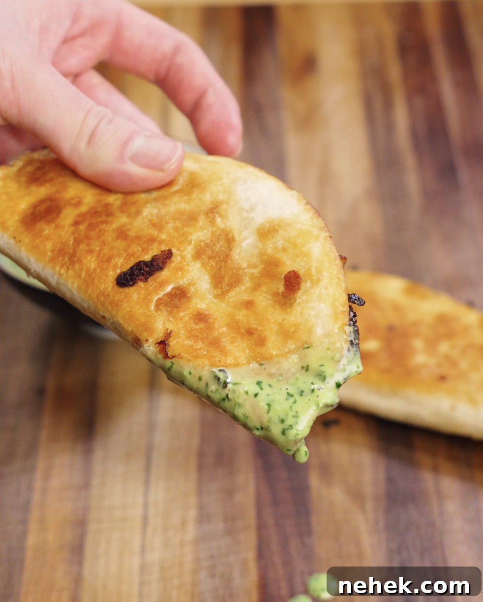 Golden crispy chicken taco folded in a flour tortilla and filled with juicy seasoned chicken, melted cheese, and a generous drizzle of creamy cilantro mayo sauce, ready to serve.