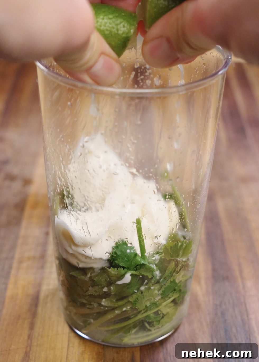 Fresh cilantro, mayonnaise, lime juice, salt, and water blended together in a tall container to create a smooth and creamy cilantro mayo sauce for crispy chicken tacos.