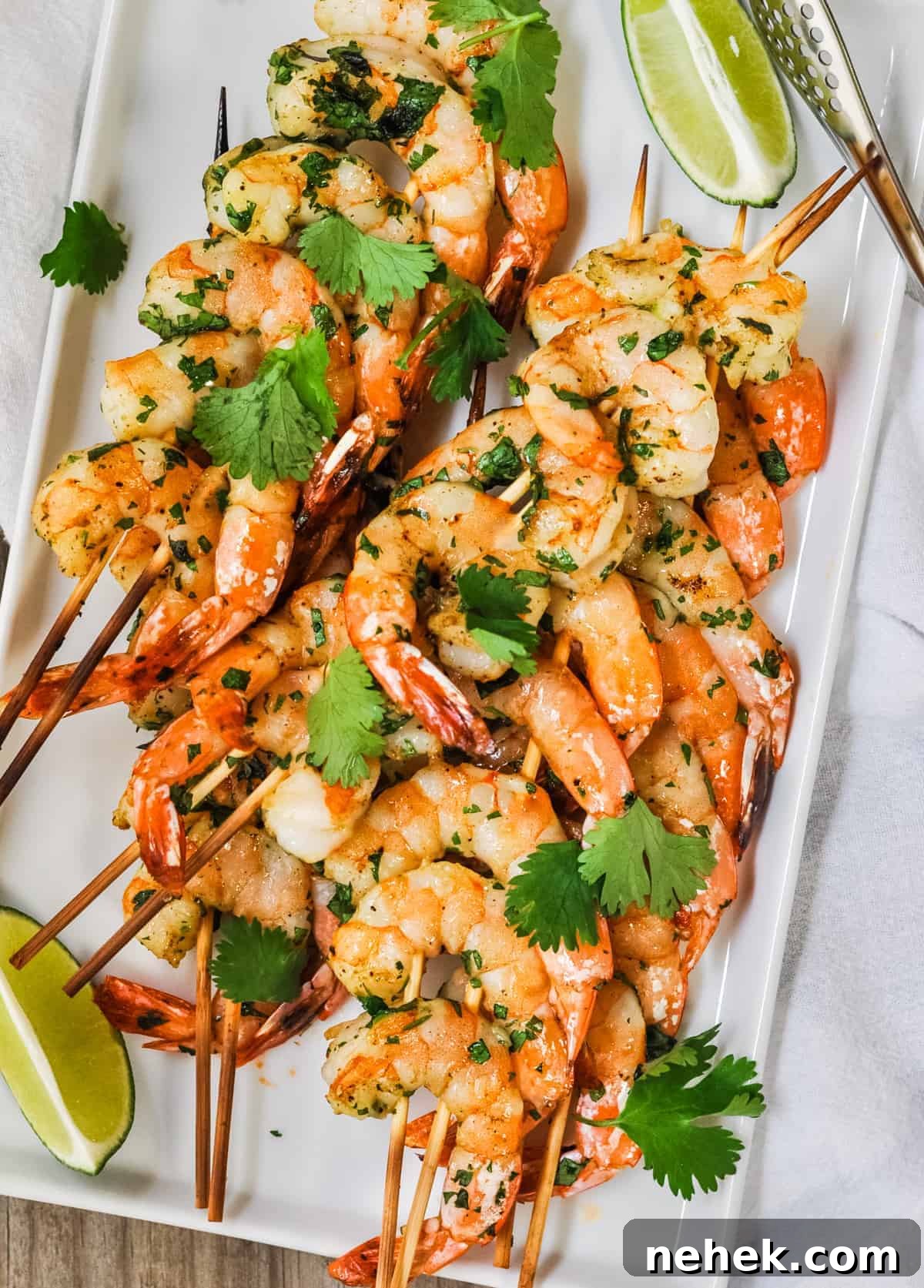 Spicy Grilled Shrimp Recipe with Cajun Marinade and Garlic Butter 4 Spicy Grilled Shrimp served on a white platter with lime wedges and photographed from the top.
