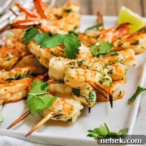 Spicy Grilled Shrimp Recipe with Cajun Marinade and Garlic Butter 5 Spicy Grilled Shrimp served on a white platter with lime wedges.