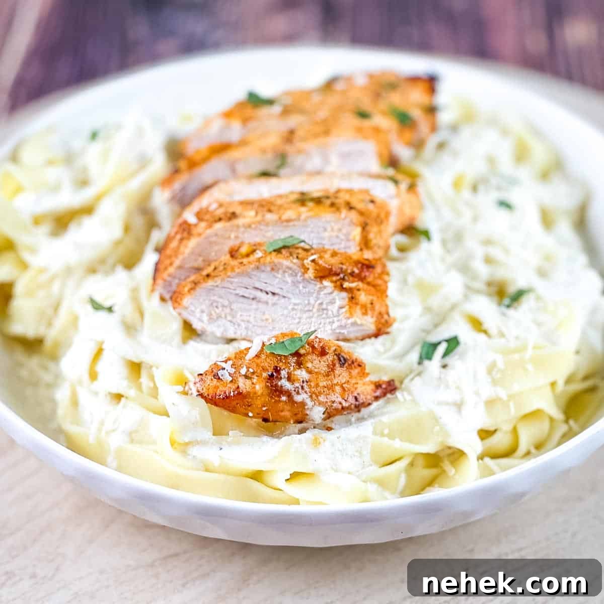 Air fryer chicken alfredo in a white pasta bowl, garnished with fresh herbs.