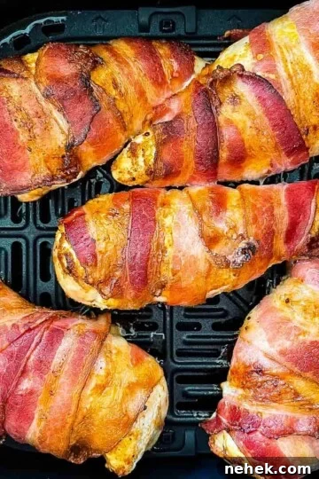 Cooked bacon-wrapped chicken in the air fryer basket.
