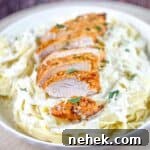 Air fryer chicken alfredo in a white pasta bowl, garnished with fresh herbs.