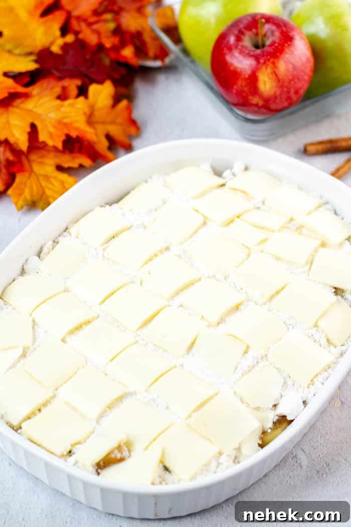 Caramel Apple Dump Cake Recipe with Homemade Sauce 6 Photo of pats of butter covering the Apple Dump Cake in a white baking dish before it goes in the oven.