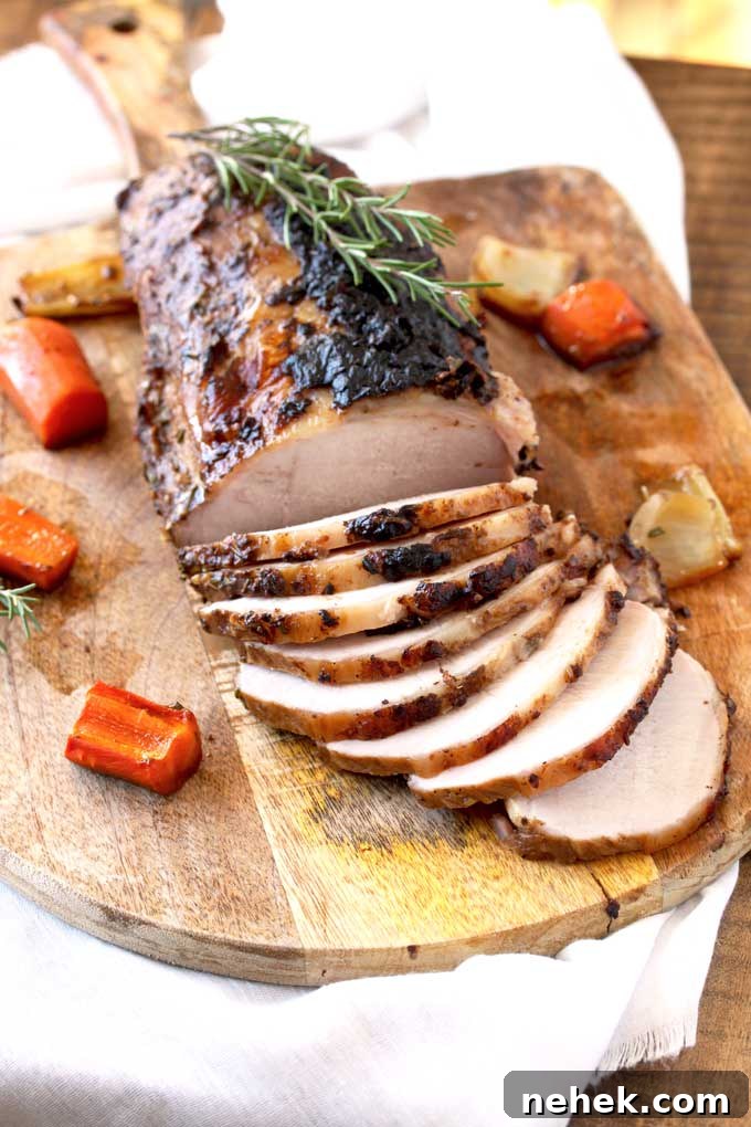 View of the roasted pork loin sliced thinly on a cutting board. You can see a thin layer of crispy tops on the slices.