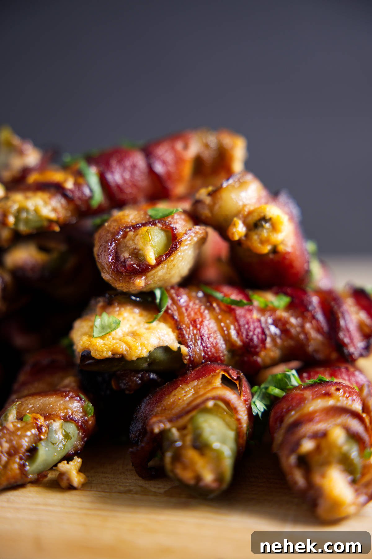 Large pile of bacon wrapped jalapeño poppers with cheese oozing out.